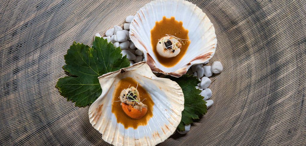 A tantalizing dish showcasing shells filled with a flavorful shellfish soup, served at Phos Restaurant