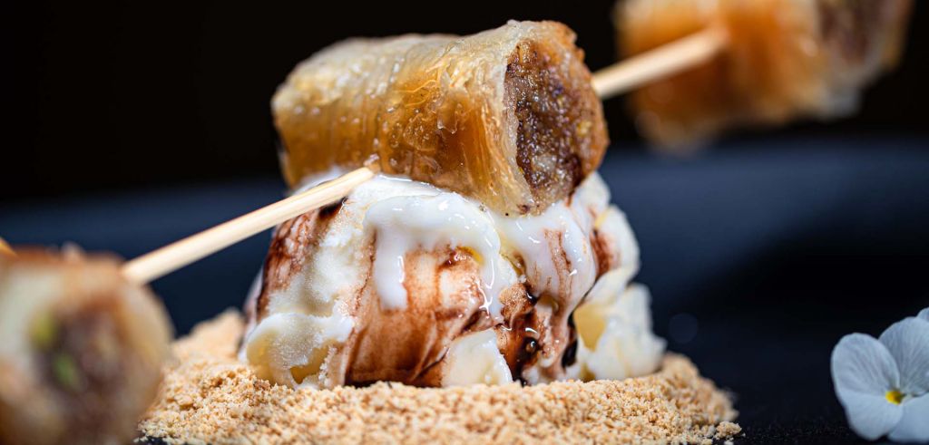 A traditional dessert of baklava served atop a scoop of ice cream