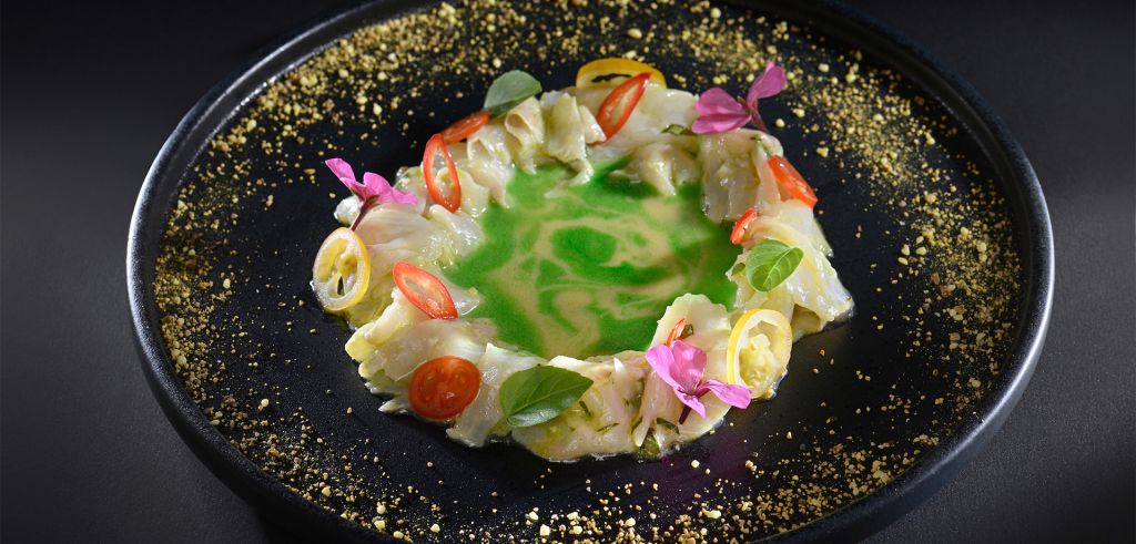 A gourmet dish presenting cabbage soup adorned with edible flowers, served at Phos Restaurant.