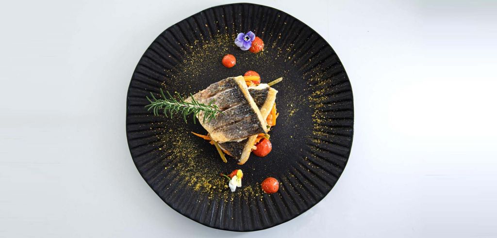 A delectable gourmet dish featuring fresh fish, rosemary and cherry tomatoes